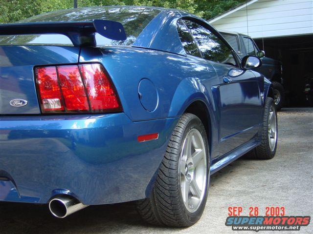 Blue 1999 Ford Mustang rear quarter panel with spoiler and Ford badge