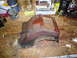 1975 Ford Ranchero - A heavily rusted car part, possibly from the undercarriage, rests on a cluttered workbench.