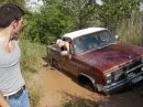 Red pickup truck stuck in mud with a person leaning out the window