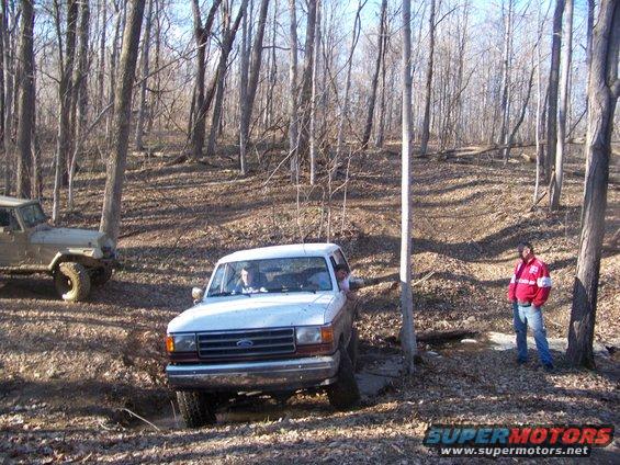 White Ford truck with a red stripe on the side, driving off-road