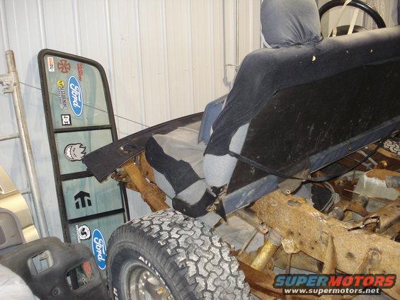 Driver's side interior of a disassembled Ford truck, showing the seat and door frame with Ford stickers