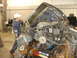 1993 Ford F-150 - The engine bay of a severely damaged 1993 Ford F-150 is examined by a person in a workshop.