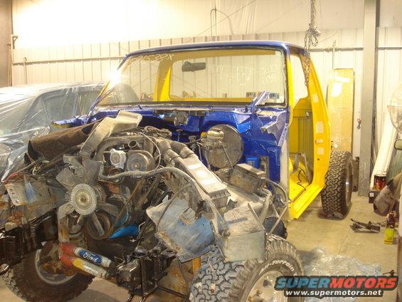 1993 Ford F-150 cab with engine removed, undergoing restoration. Blue and yellow paint scheme