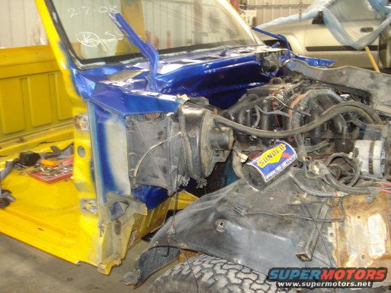 Truck engine bay with blue and yellow paint, "2-7-08" written on windshield