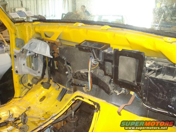 Disassembled dashboard interior with yellow painted metal and exposed wiring