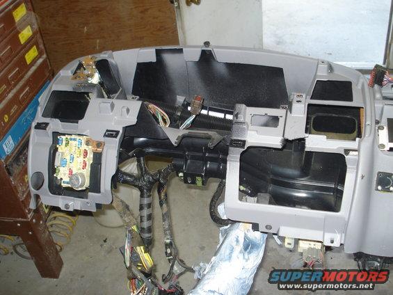 Disassembled dashboard assembly showing wiring and fuse box