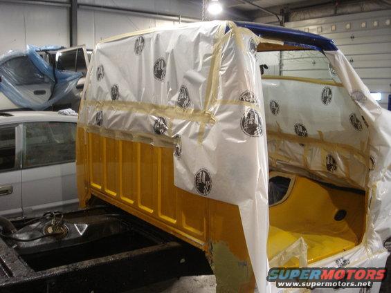 1993 Ford F-150 cab covered in protective plastic for painting, with another vehicle in the background