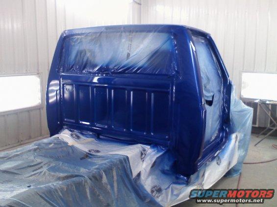 1993 Ford F-150 cab in a paint booth, covered in blue paint and plastic sheeting