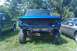 1993 Ford F-150 - Front view of a blue 1992 Ford F-150 truck with its grille and headlights removed, parked next to other vehicles.