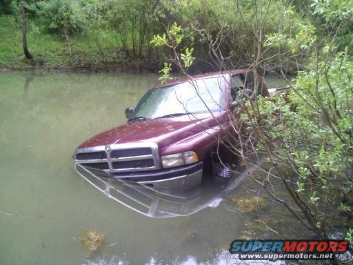 Maroon pickup truck partially submerged in water, front grille visible