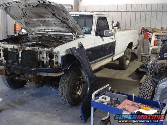 Ford F-250 truck with hood open, front end disassembled, and fender removed. Tools and parts are nearby