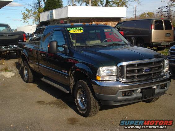 Dark green Ford F-Series truck, 3/4 front view, chrome grille, visible 'DIESEL 2003' sticker on windshield