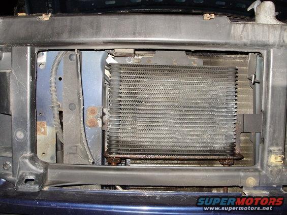 1995 Ford Bronco transmission cooler mounted behind grille, showing some rust and dirt