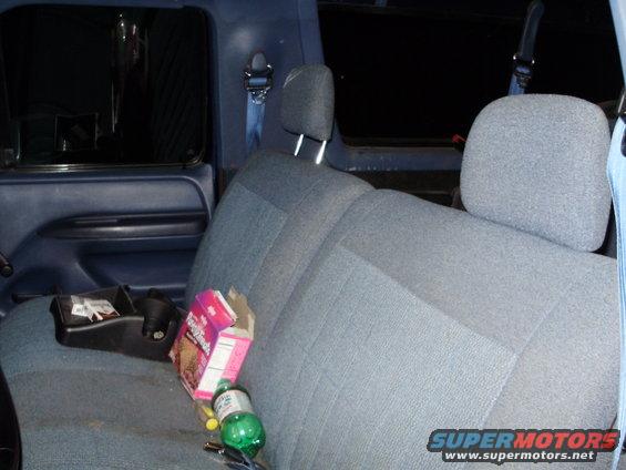 Interior shot of a blue truck's back seat with a box of cookies and a soda bottle on it