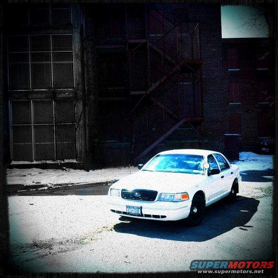 White 2000 Ford Crown Victoria parked in front of a brick building with a fire escape