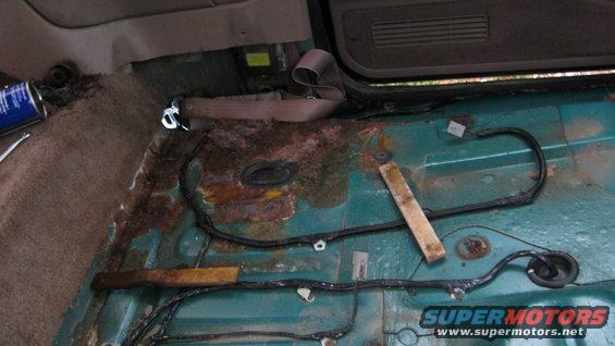Vehicle interior floor with extensive rust and exposed wiring