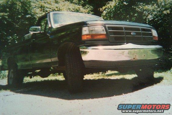 Dark green Ford F-Series truck, front quarter view. Grille and headlights visible