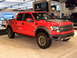 2011 Ford F-150 - A red 2011 Ford F-150 Raptor pickup truck is displayed at an auto show.