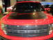 2011 Ford F-150 - Front view of a red Ford F-150 Raptor truck, showing the grille and hood details.