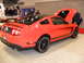 2012 Ford Mustang - A red 2012 Ford Mustang Boss 302 is displayed with its hood open, parked next to another vehicle.