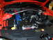 2012 Ford Mustang - The engine bay of a 2012 Ford Mustang features blue valve covers and a silver strut tower brace.