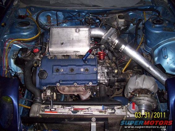 Engine bay with blue valve cover, intercooler piping, and turbocharger. Date stamp 03/31/2011