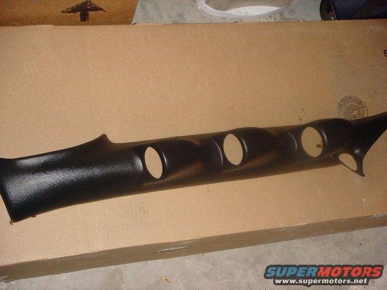 Black plastic gauge pod with four circular openings, resting on a cardboard box