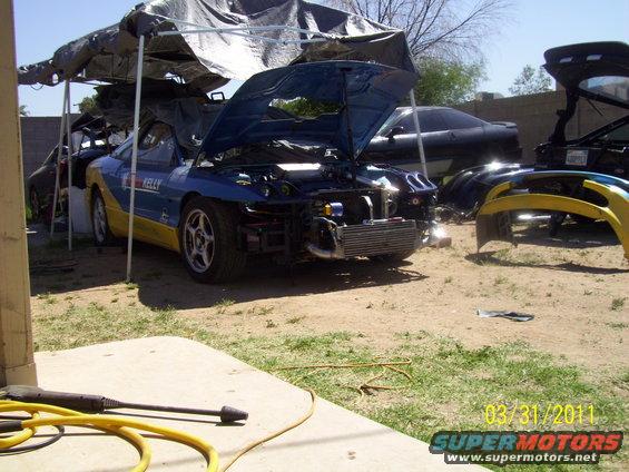 Blue and yellow car with hood open, front bumper removed, intercooler visible