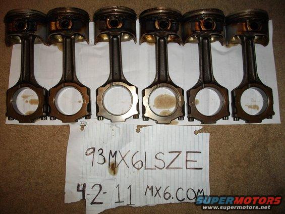 Six engine pistons with connecting rods laid out, with a note that says '93 MX6LSZE 42-11 MX6.COM'