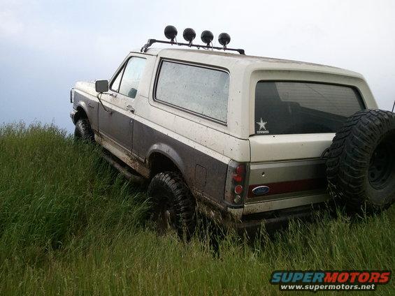 Ford Bronco climbing a grassy hill, spare tire mounted on back