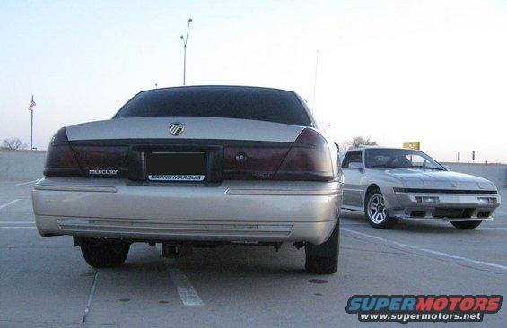Rear of silver 2000 Mercury Grand Marquis with another silver car behind it