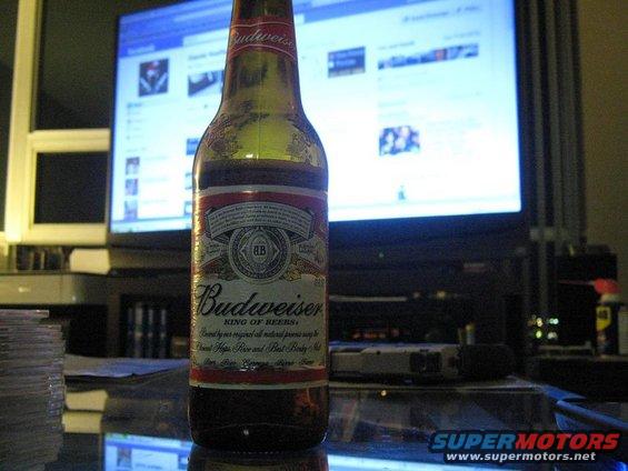 Budweiser bottle in front of a computer screen displaying Facebook