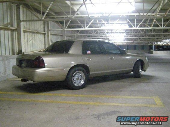 Tan 2000 Mercury Grand Marquis parked in a garage. It has aftermarket wheels and tinted windows