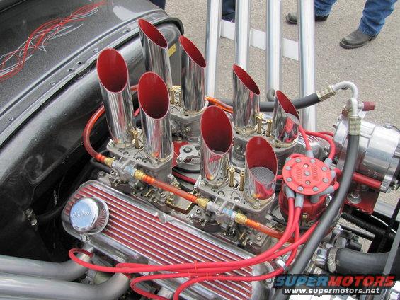 Engine with chrome valve covers, eight red-tipped exhaust pipes, and dual carburetors