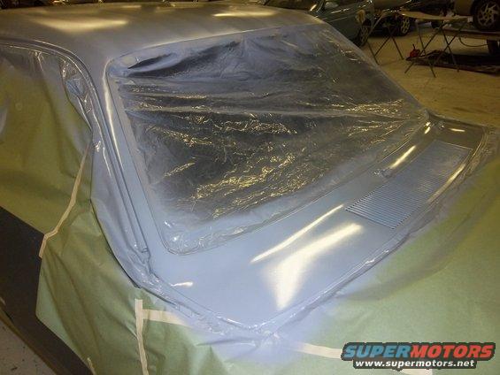 Car hood and windshield covered in plastic sheeting, with masking paper on the sides. A vent is visible on the hood