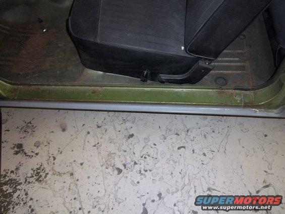 Green car interior showing a black seat, door sill, and floor