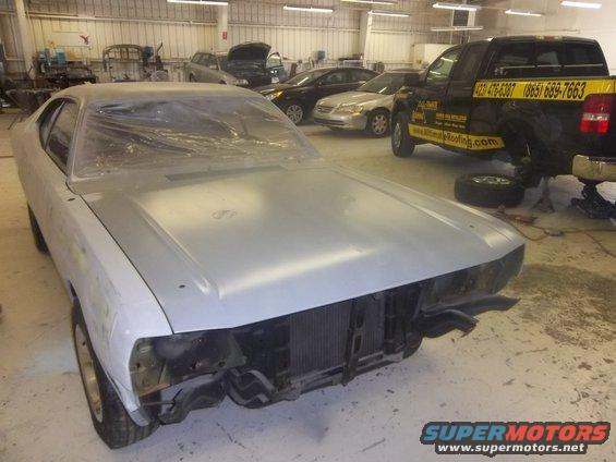 1971 Dodge Dart body in primer, front view, in a workshop with other cars and a truck