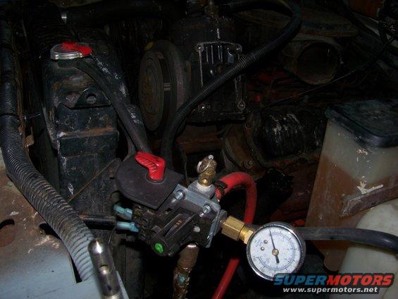 Engine bay showing a pressure gauge connected to a valve assembly near the radiator