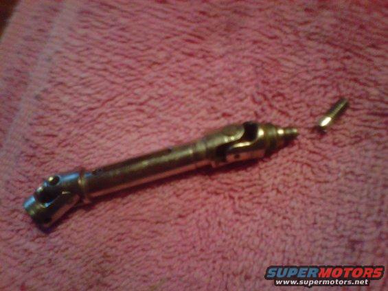 Metal automotive part on pink fabric with SUPERMOTORS.NET text