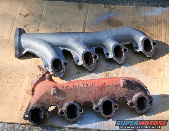 Two exhaust manifolds, one rusty red and one silver, laid out on cardboard