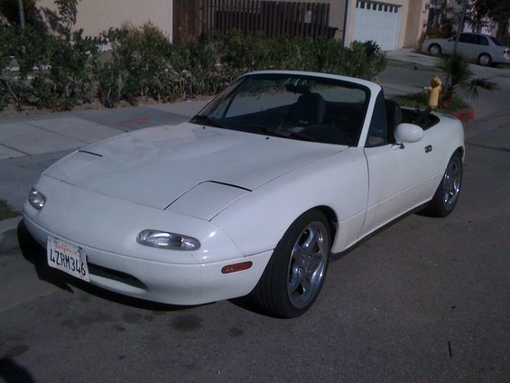 White convertible sports car with pop-up headlights and a California license plate