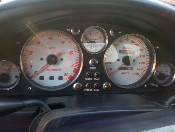 Car dashboard with tachometer, speedometer, oil pressure, fuel, and water gauges. Lights for 'LIGHT', 'CHARGE BRAKE', and 'EX-HEAT BELTS' are visible