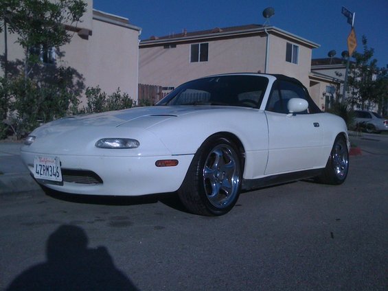 White 1991 Mazda Miata convertible with chrome wheels parked on a street