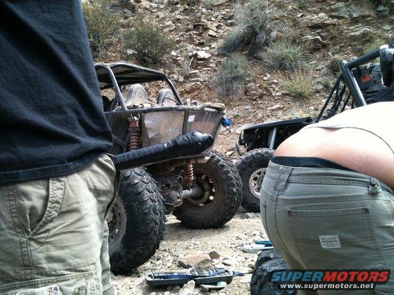 Two off-road buggies parked on a rocky trail with people nearby