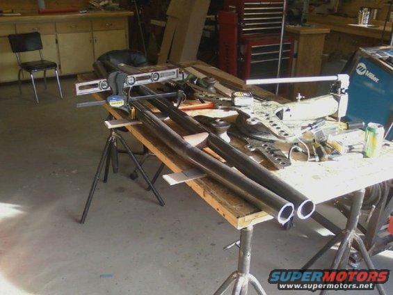 metal pipes clamped to a workbench with tools and a pipe bender nearby