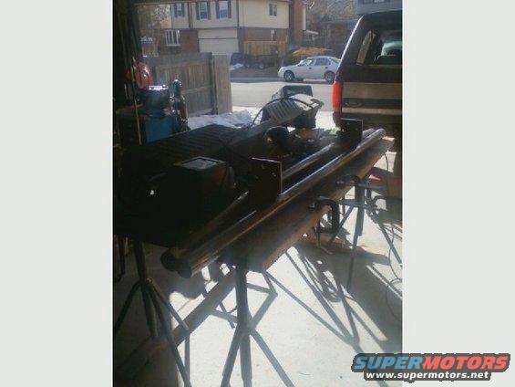 Truck bed with metal bars, rear view. A dark SUV is parked behind