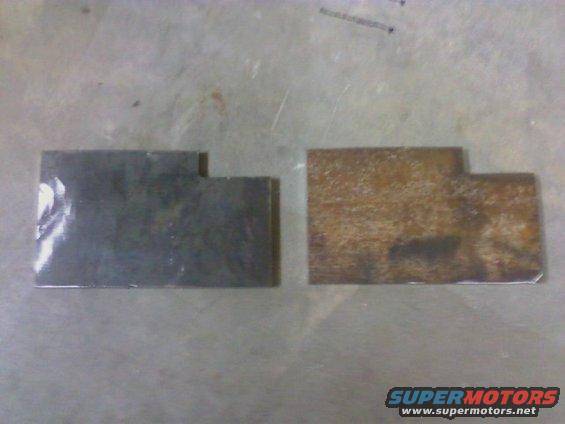 two metal brackets, one dark and one rusty, on a flat surface