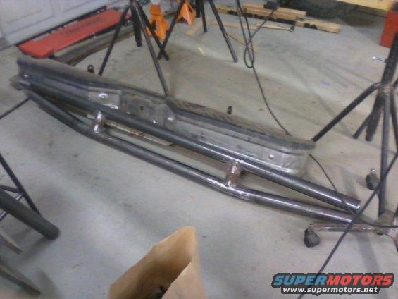 Custom metal brush guard attached to a vehicle bumper, lying on a concrete floor