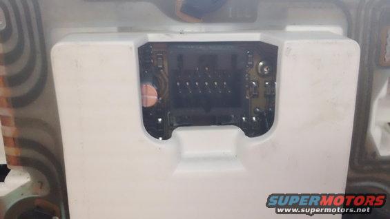 Close-up of a white plastic housing with a circuit board visible inside. Some copper traces and electronic components are present