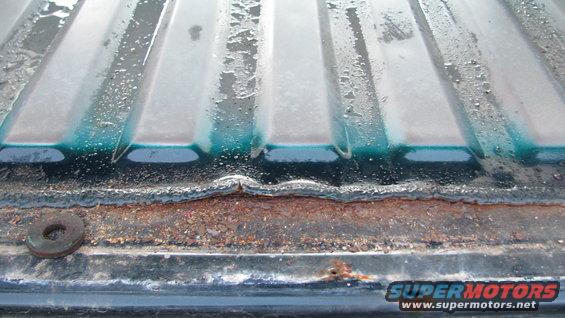 Rusted tailgate edge with teal paint showing through
